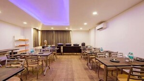 A conference room with multiple tables and chairs, a podium, and a large window with curtains. - hotel noida express (Noida)