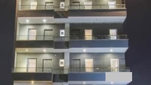 A multi-story building with balconies and windows, illuminated by exterior lighting. - hotel noida express (Noida)