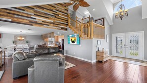 Een ruime woonruimte met een modern design, met een houten plafond, een trap en een groot raam.