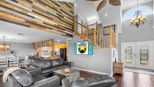 Een ruime woonkamer met een modern design, met een leren zithoek, een houten salontafel en een groot televisiescherm.