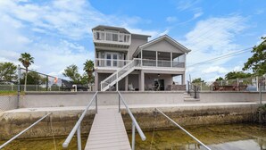 Een gebouw met twee verdiepingen, een balkon en een steiger die uitkomt op een waterpartij.