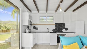A modern kitchen with white cabinets, a black hexagonal backsplash, and a large window overlooking a grassy area.