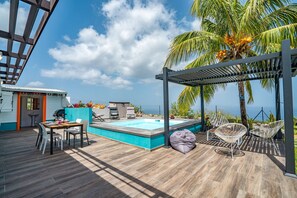 Un área de piscina en la azotea con terraza de madera, sillas de descanso y una pérgola.