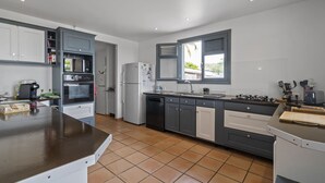 Una cocina moderna con armarios grises, una isla central y un ventanal que proporciona luz natural.