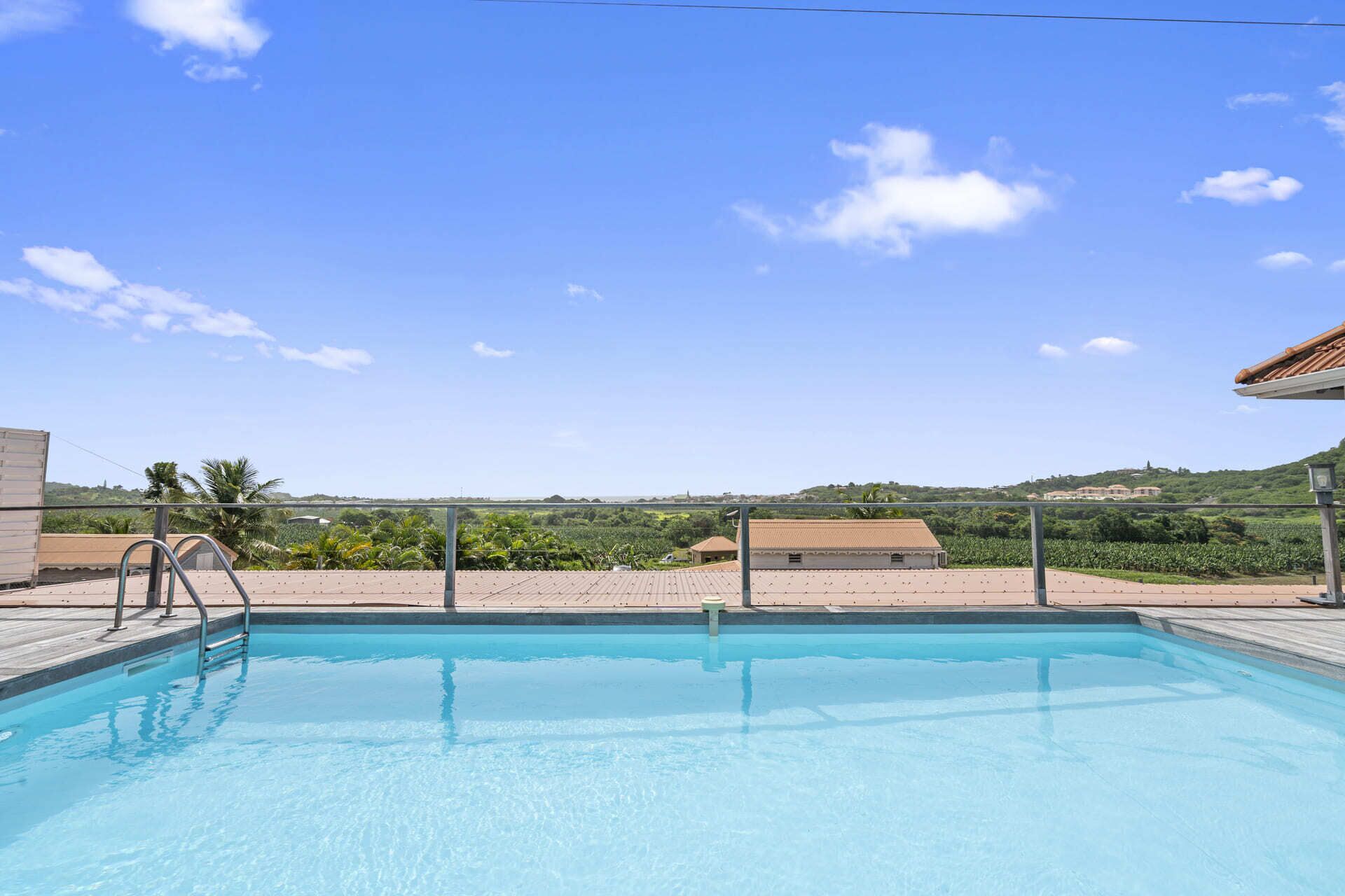 A swimming pool with a clear view of the surrounding landscape, including buildings and greenery.