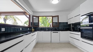 Una cocina moderna con armarios blancos, encimeras negras y un refrigerador Bosch.