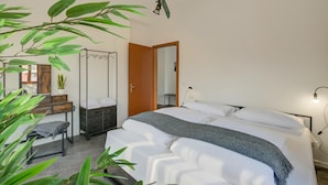 Una camera da letto con un letto, una scrivania, una sedia, un armadio e uno specchio.