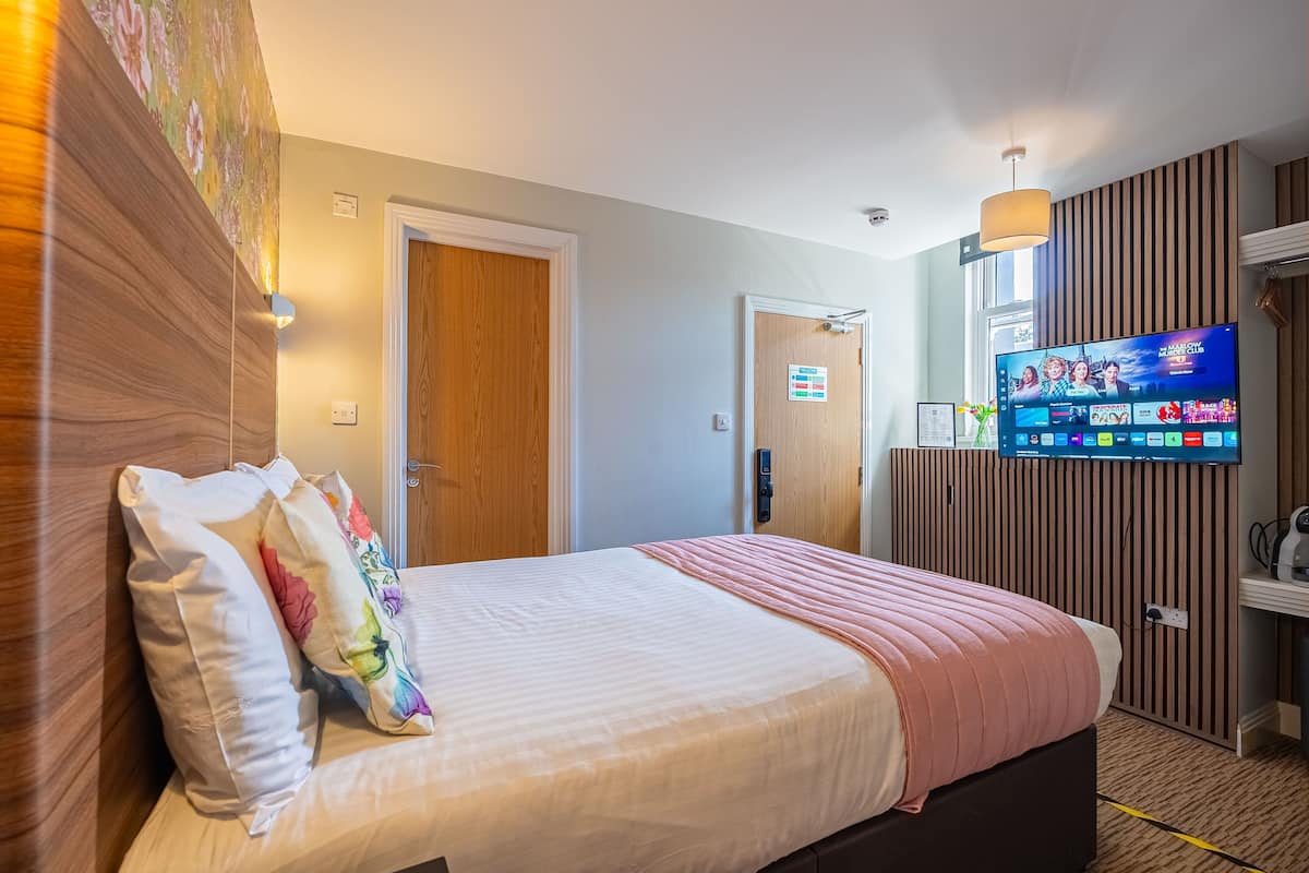 Une chambre d’hôtel avec un lit, une télévision et un panneau mural en bois.