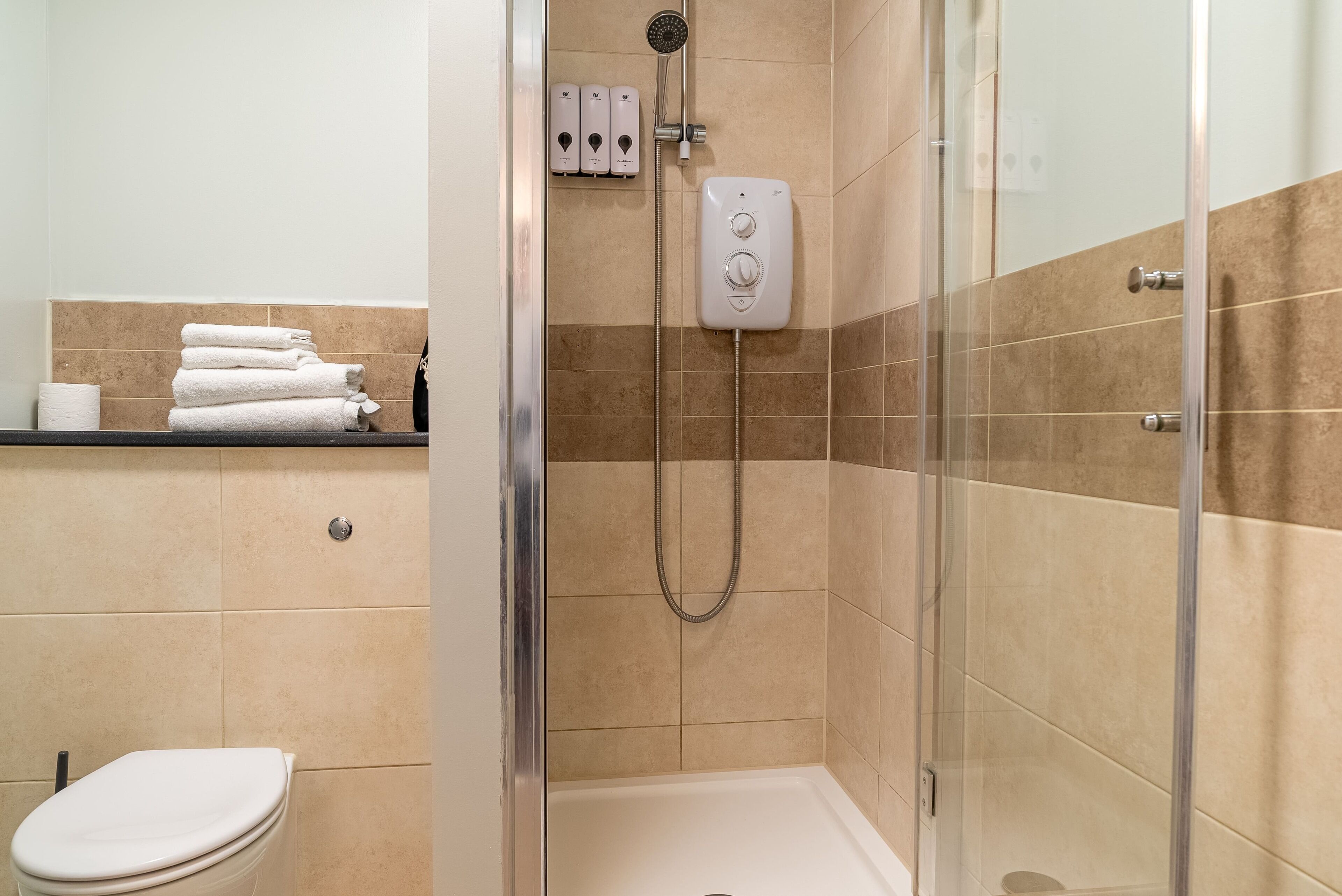 Un baño moderno con ducha de vidrio, inodoro y perchero para toallas.