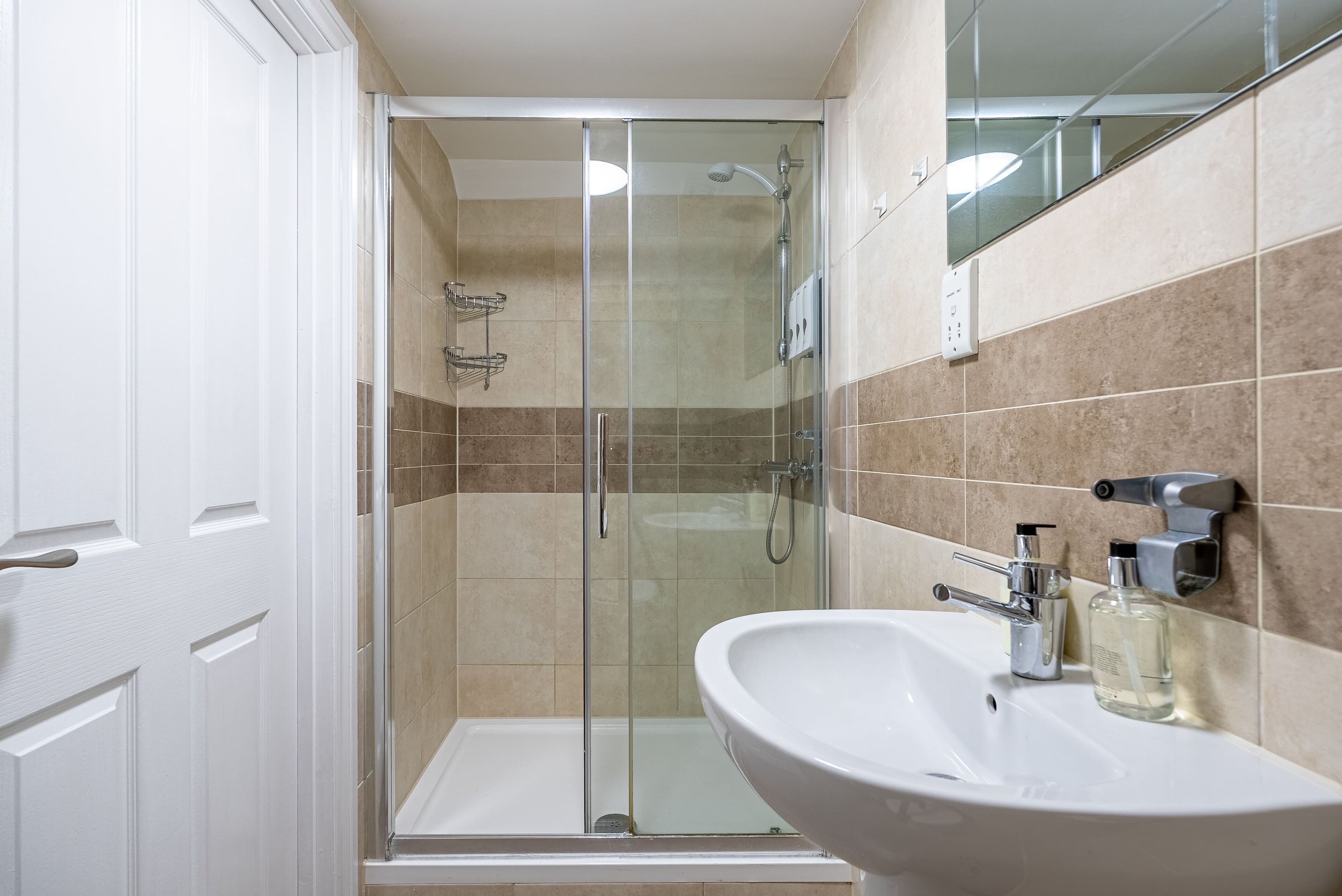 A modern bathroom with a glass-enclosed shower, a white sink, and a mirror.