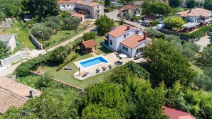 An aerial view of a residential area with houses, a swimming pool, and surrounding greenery. - Pool House Robertino (Tar-Vabriga)