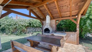 An outdoor patio with a stone fireplace, wooden benches, and a brick oven. - Pool House Robertino (Tar-Vabriga)