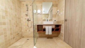 Une salle de bain moderne avec une douche à l’italienne en verre, un meuble-lavabo en bois et un grand miroir.