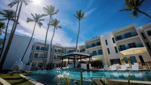 Un hôtel moderne doté d’une piscine, de palmiers et offrant une vue sur un ciel bleu azur.