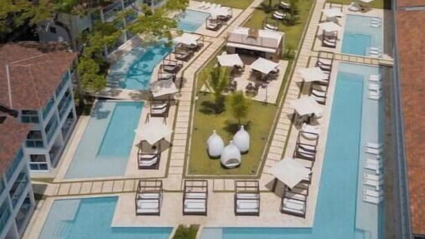 Een resort met meerdere zwembaden, ligbedden en uitzicht op de oceaan.