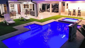 Una piscina con elemento d'acqua, circondata da lettini e un'area bar.
