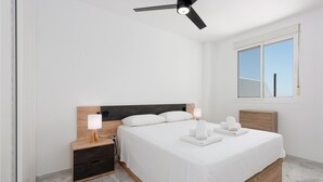 A bedroom with a bed, bedside tables, a ceiling fan, a window, and a nightstand. - Hacienda Casares 2053 Geranio (Casares)