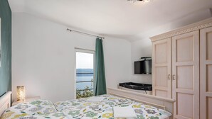 Een slaapkamer met een bed, een kledingkast, een televisie en een raam met uitzicht.
