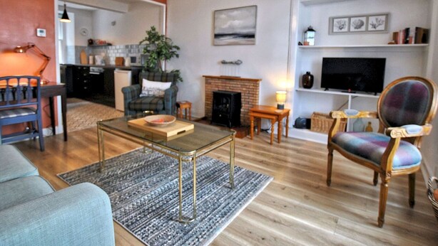 A living room with a sofa, a glass coffee table, a fireplace, and a television. - Harbour Haven- idyllic coastal retreat (Anstruther)