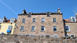 A multi-story stone building with multiple windows and a red-tiled roof. - Harbour Haven- idyllic coastal retreat (Anstruther)