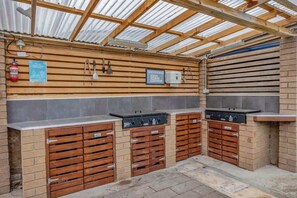 An outdoor kitchen area with a grill, storage cabinets, and a fire extinguisher.