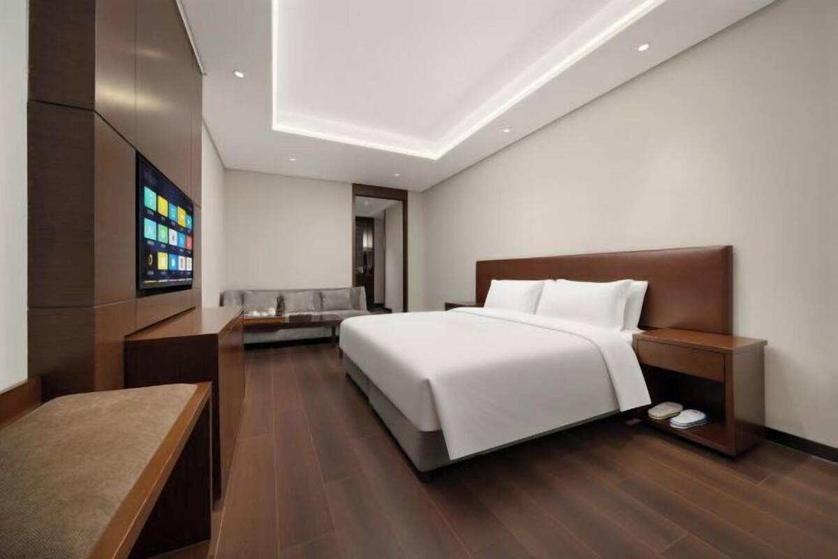 Ein modernes Hotelzimmer mit einem großen Bett, Nachttischen, einem Fernseher und einem Schreibtisch.