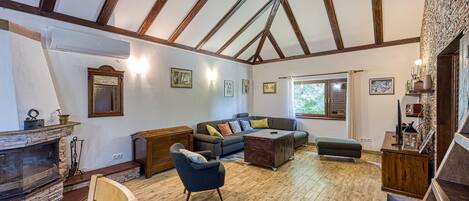 A spacious living room with a fireplace, wooden beams, and a large sectional sofa.