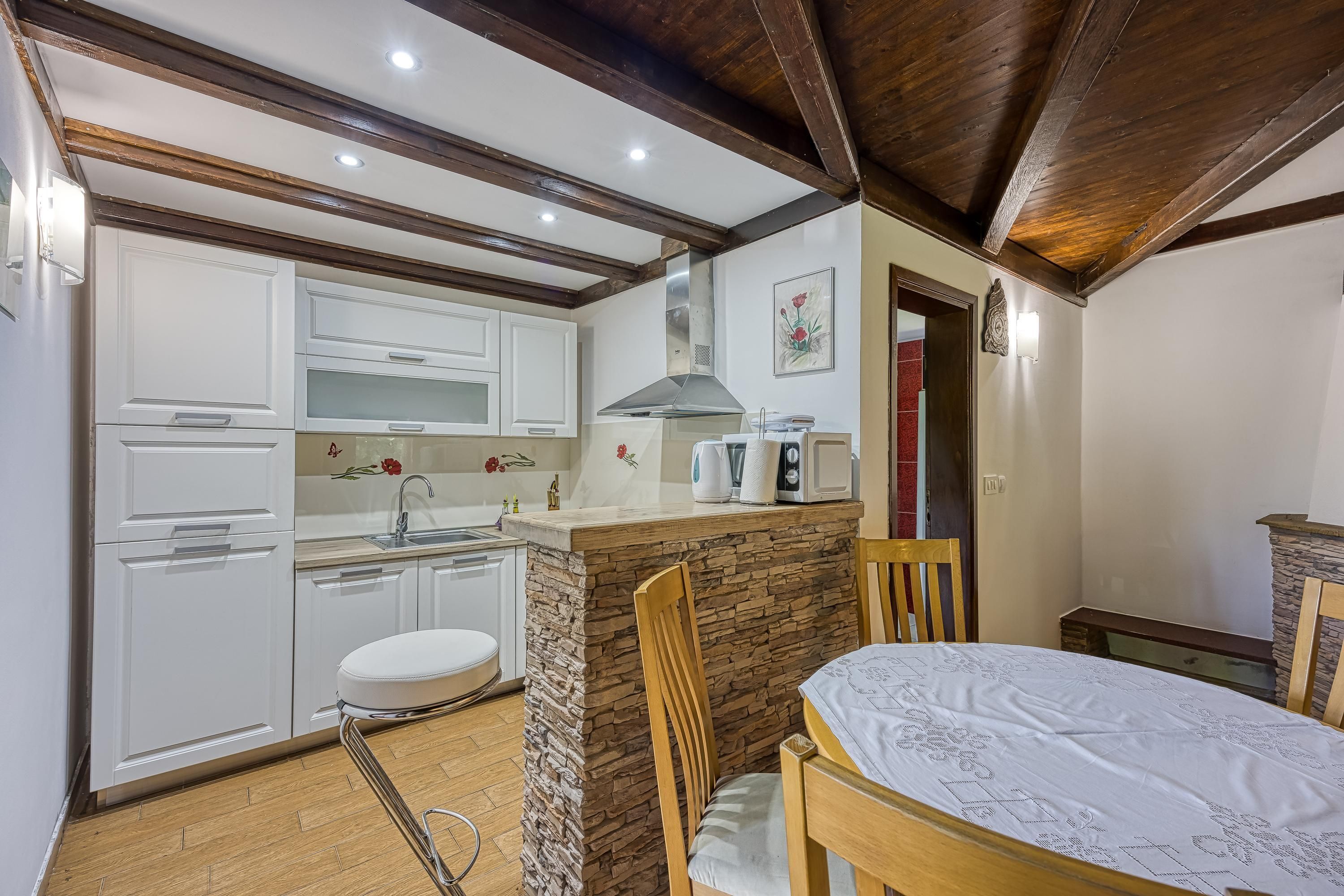A compact kitchen with white cabinets, a stone island, and a dining area with wooden chairs and a table.