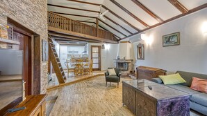 Amplia sala de estar con piso de madera, un sofá, una mesa de centro y una chimenea.