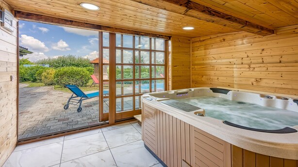 Una cabaña de madera con jacuzzi y un patio con una silla.