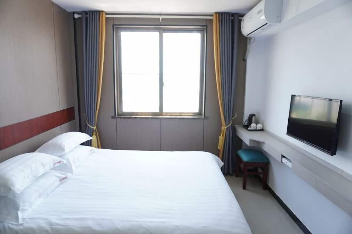 Ein Hotelzimmer mit Bett, Vorhängen, einem Fernseher und einer Klimaanlage.
