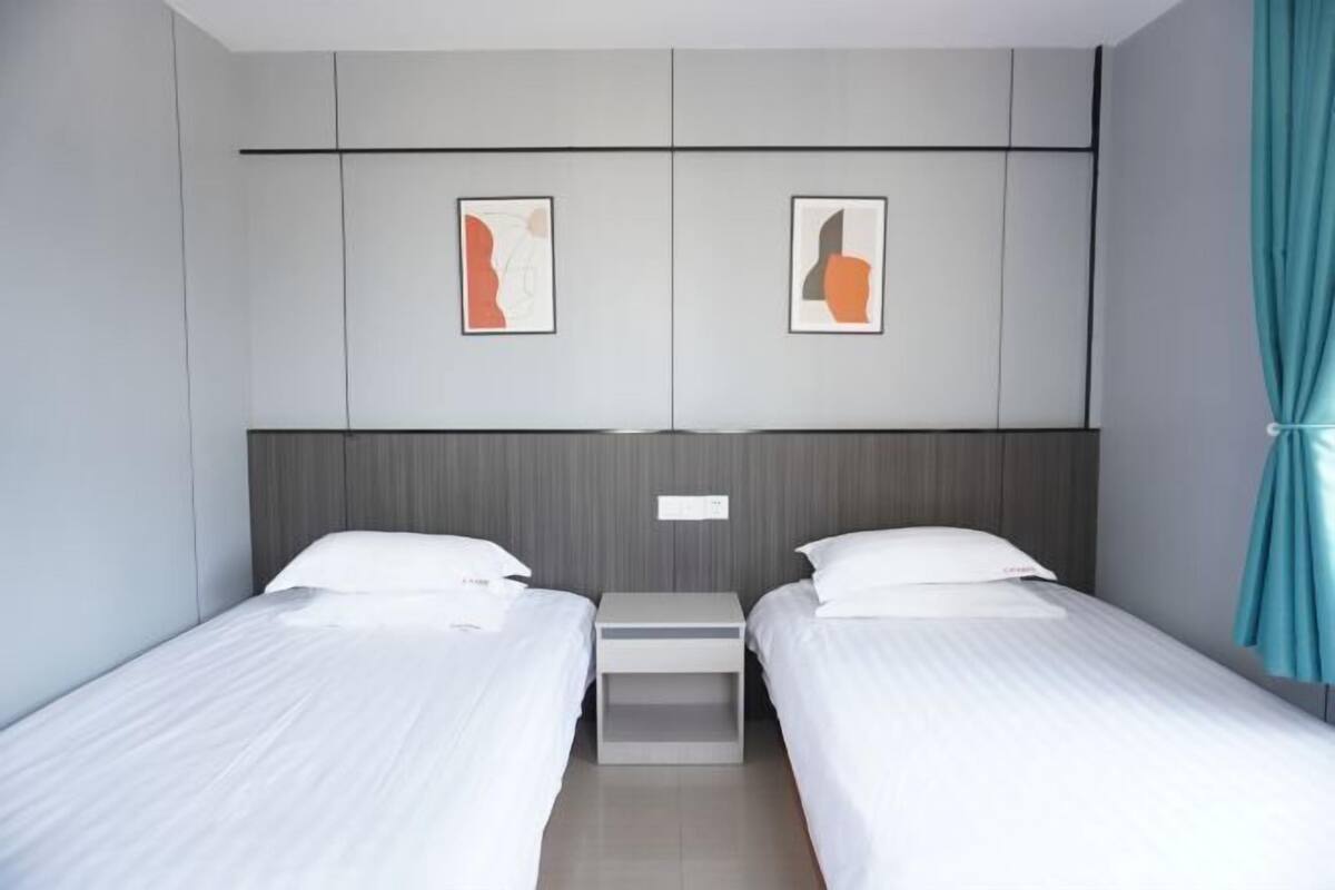 Ein Hotelzimmer mit zwei Betten, einem Nachttisch und einem Bild an der Wand.