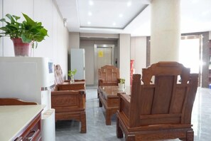 A hotel lobby with wooden furniture, a refrigerator, and a potted plant. - Anqing No.1 Pier Hotel (Anqing)