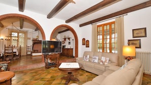 A living room with a television, sofa, and coffee table. There are arched doorways and a fireplace. - Villa Cerbaie in Fucecchio (Fucecchio)