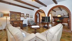A living room with two beige sofas, a wooden coffee table, a television, and a bar area with stools. - Villa Cerbaie in Fucecchio (Fucecchio)