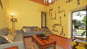 A living room with a sofa, a coffee table, and a patterned rug. There is a chandelier and a wall with motivational words.