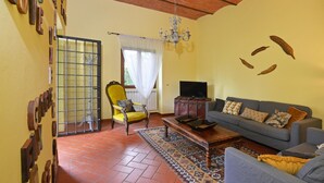 A living room with a sofa, armchair, coffee table, television, and decorative items on the wall.
