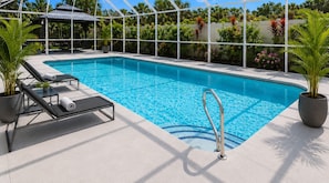 A rectangular indoor swimming pool with clear blue water, surrounded by a white deck with lounge chairs and potted plants. - Walk to Siesta Key Beach! (Siesta Key)