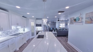A modern kitchen with white cabinetry, a marble countertop, and a central island with a sink. - Walk to Siesta Key Beach! (Siesta Key)