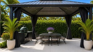 A covered outdoor dining area with a table and chairs, a grill, and potted plants. - Walk to Siesta Key Beach! (Siesta Key)