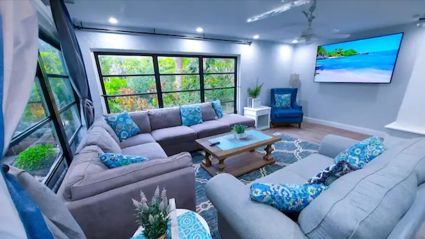 A modern living room with a sectional sofa, a coffee table, and a large window with a view of greenery. - Walk to Siesta Key Beach! (Siesta Key)