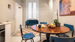 Un coin repas avec une table ronde en bois, des chaises bleues, une plante en pot et un tableau accroché au mur.