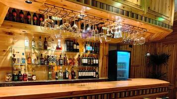 A bar area with wooden paneling, a long counter, and multiple stools.