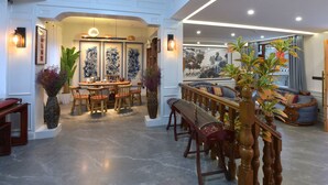 A spacious dining area with a high ceiling, a central table surrounded by chairs, and a decorative railing. - yunlushanju (Xiangxi)