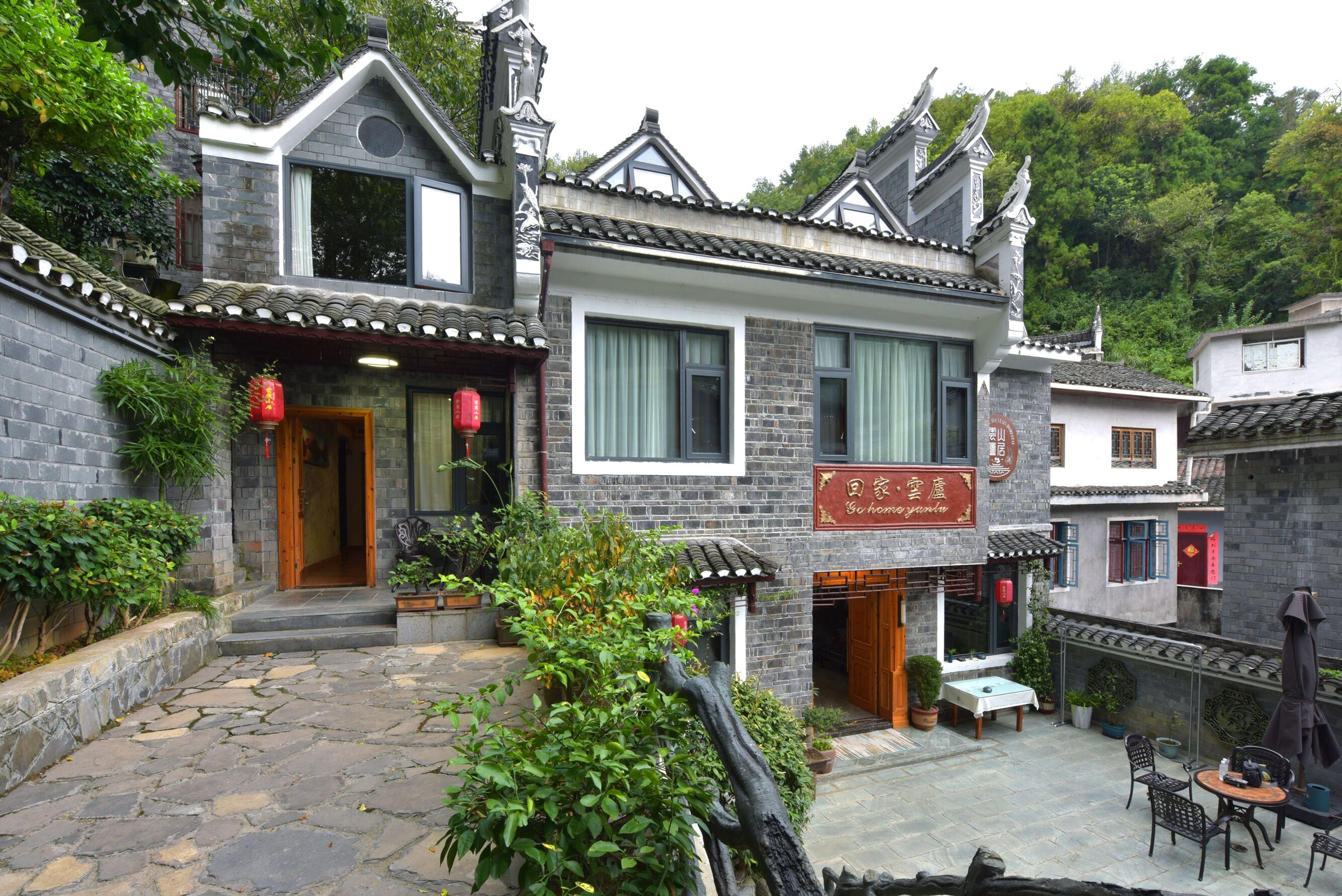 A traditional Chinese courtyard with stone paving, a wooden door, and a signboard.