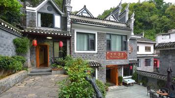 A traditional Chinese courtyard with stone paving, a wooden door, and a signboard.