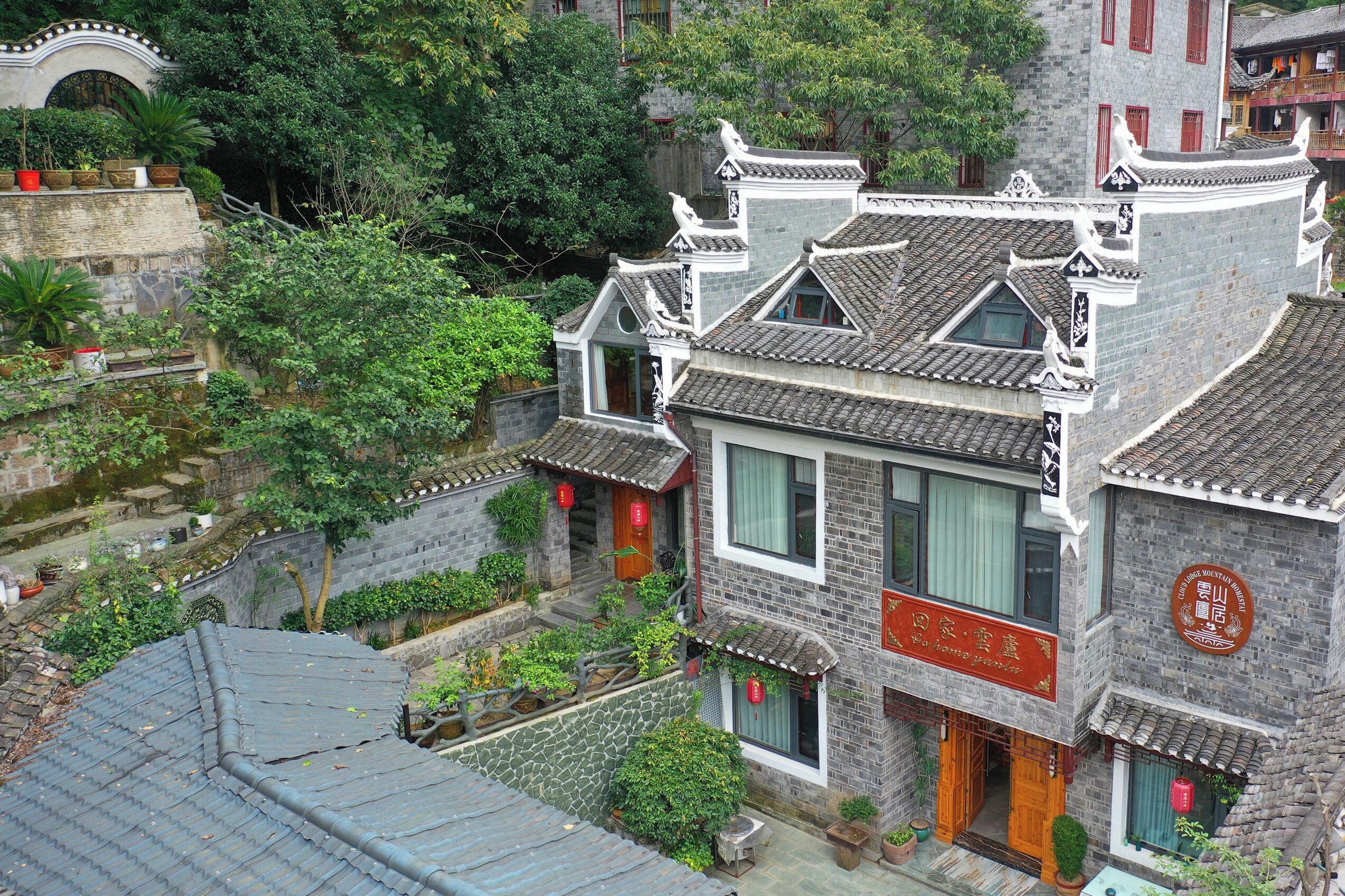 A traditional Chinese building with a tiled roof, a stone facade, and a sign indicating it is a long stay hotel.