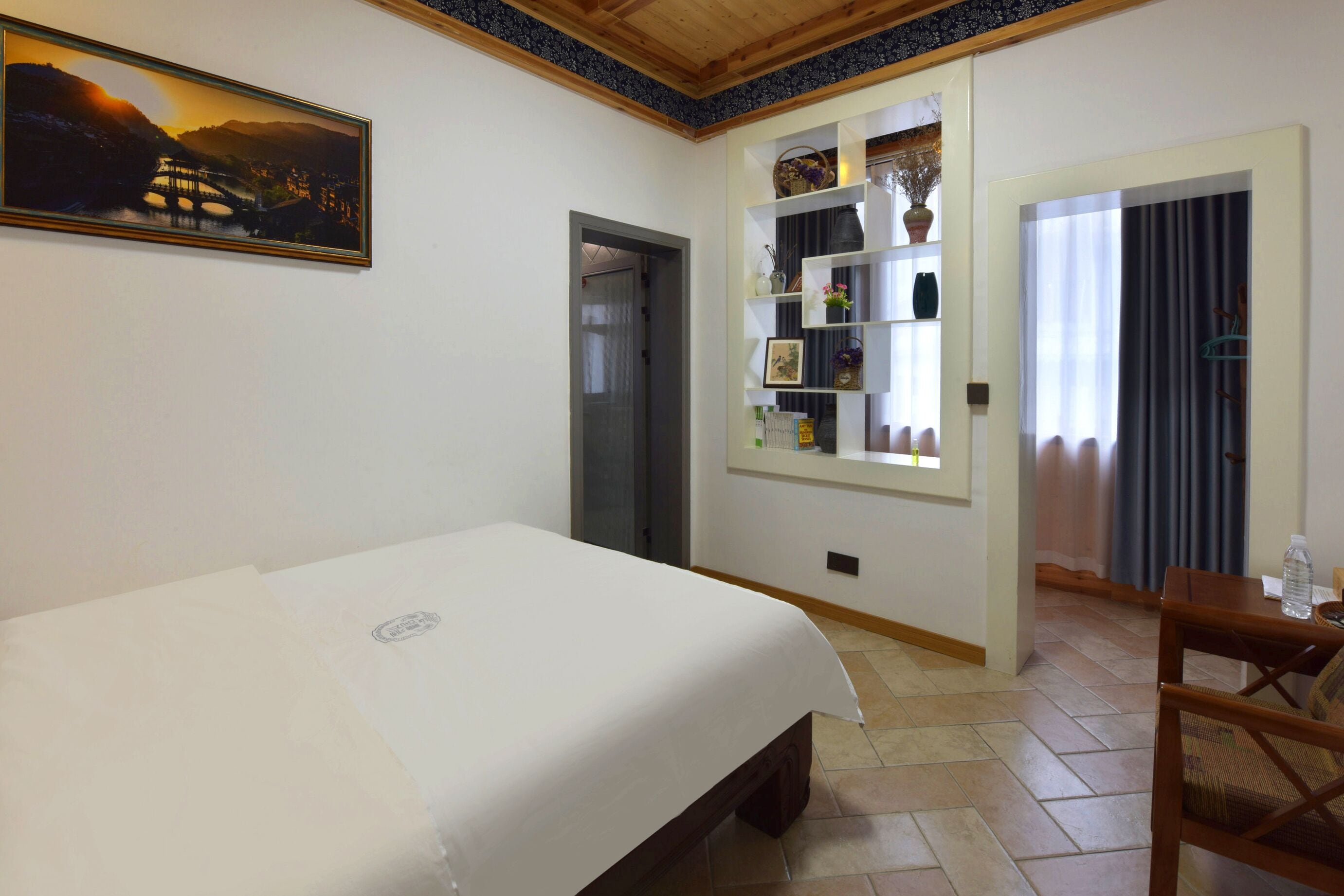 Una camera d'albergo con un letto, uno scaffale con oggetti decorativi, un quadro e vista su un ponte.