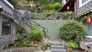 A traditional courtyard with a stone staircase, potted plants, and a small water feature. - yunlushanju (Xiangxi)