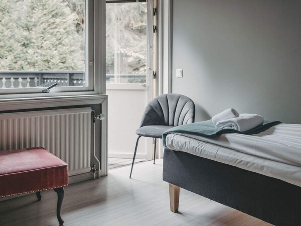 A bedroom with a bed, a chair, a bench, and a window with a view of trees. - 4 Star Holiday Home in Hisings Backa (Hisings Backa)